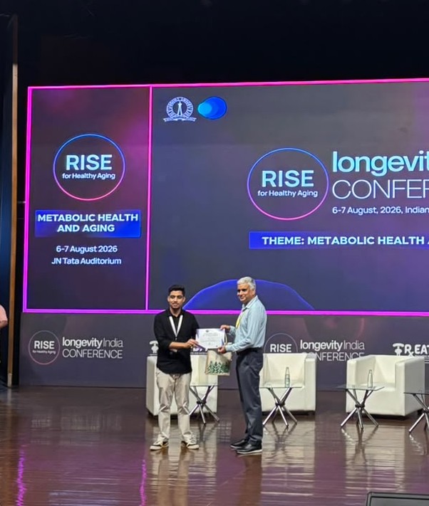 Heera Lal receiving the Best Poster Award certificate from Professor Deepak Saini on stage at the RISE Longevity India Conference